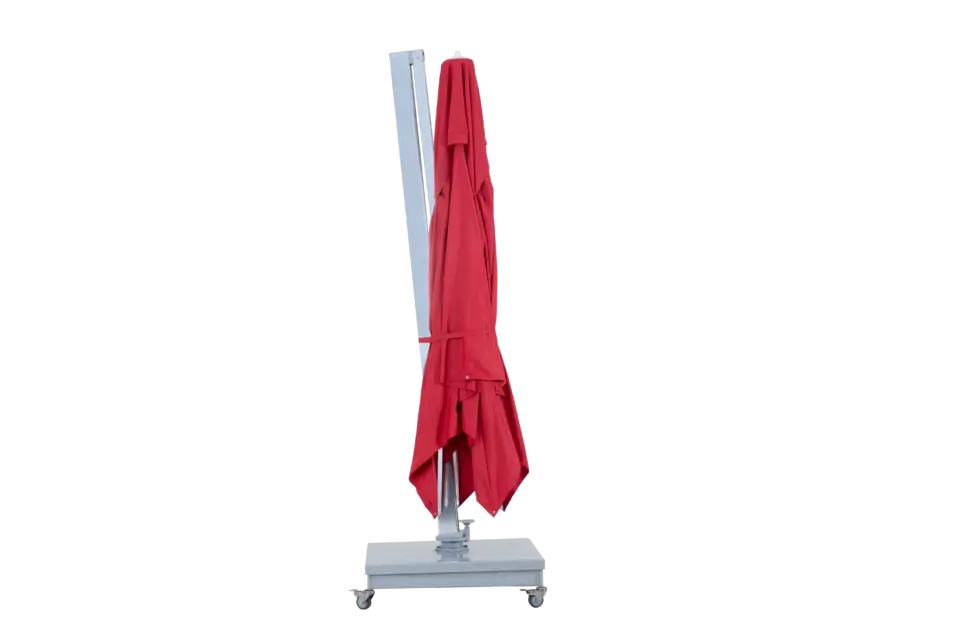 The red Aman patio umbrella in its collapsed and folded upright position, showcasing a compact profile for easy storage.