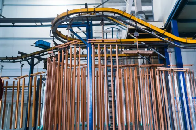 An advanced, automated overhead conveyor system transports metal umbrella components through the multi-stage surface treatment and powder coating line.