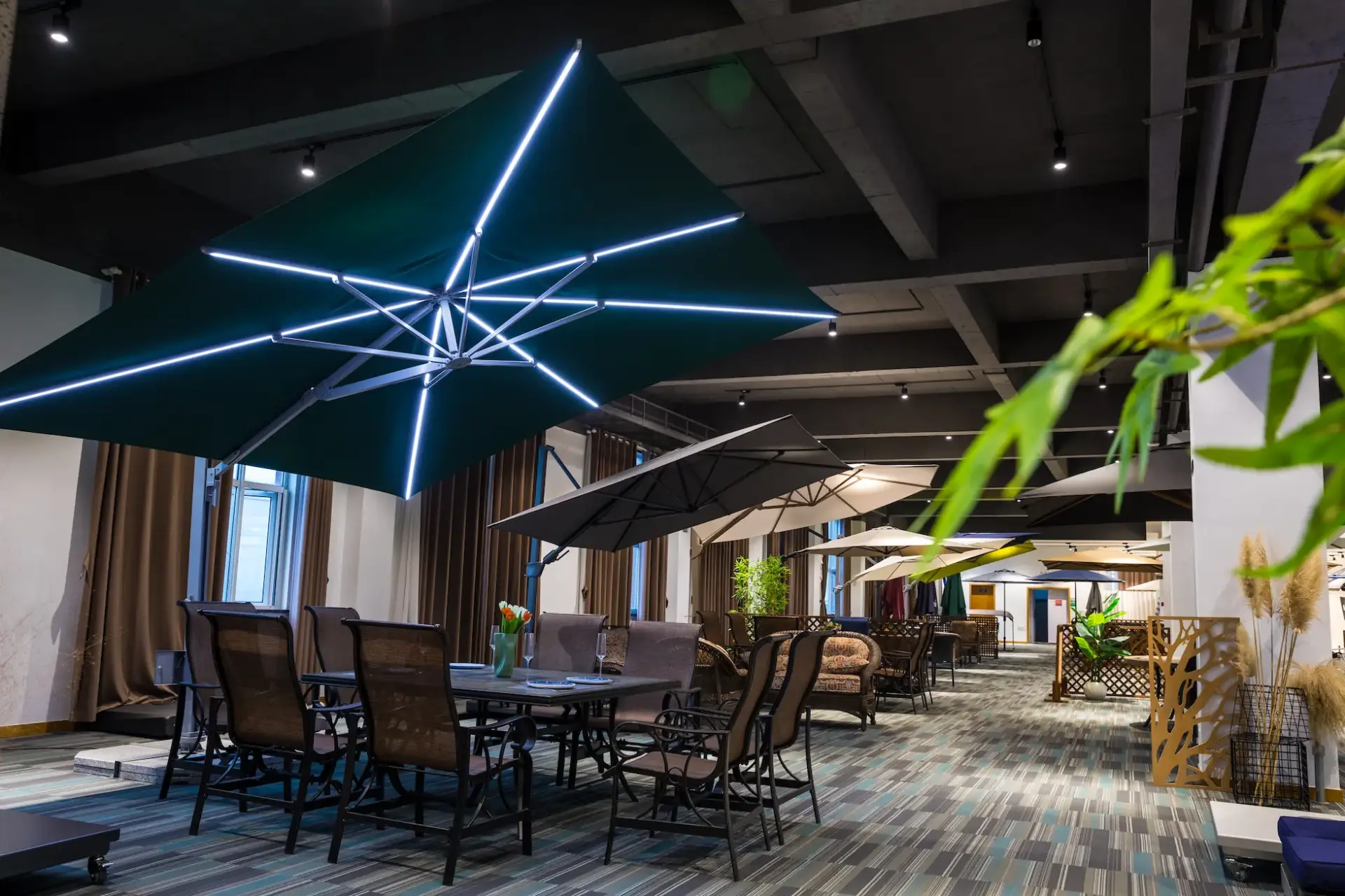 A premium dark green cantilever umbrella with its integrated LED lights turned on, creating a bright, starlike pattern, showcased in the company's modern product showroom.