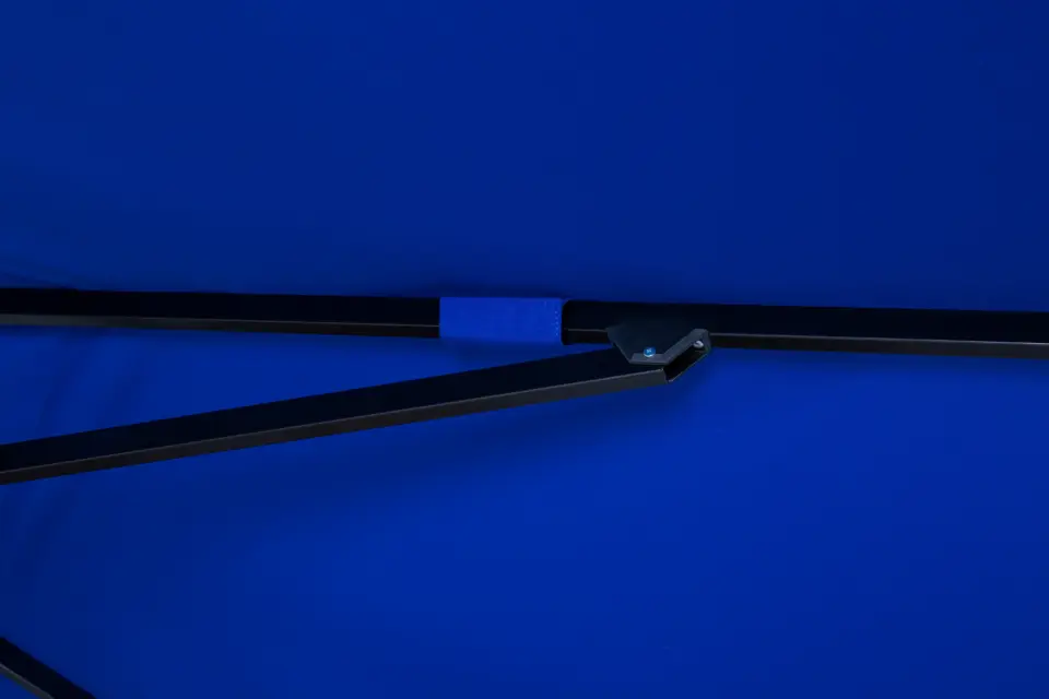 Close-up of a heavy-duty metal joint and reinforced fabric section on the frame of the blue Luciano commercial umbrella, highlighting its superior durability.