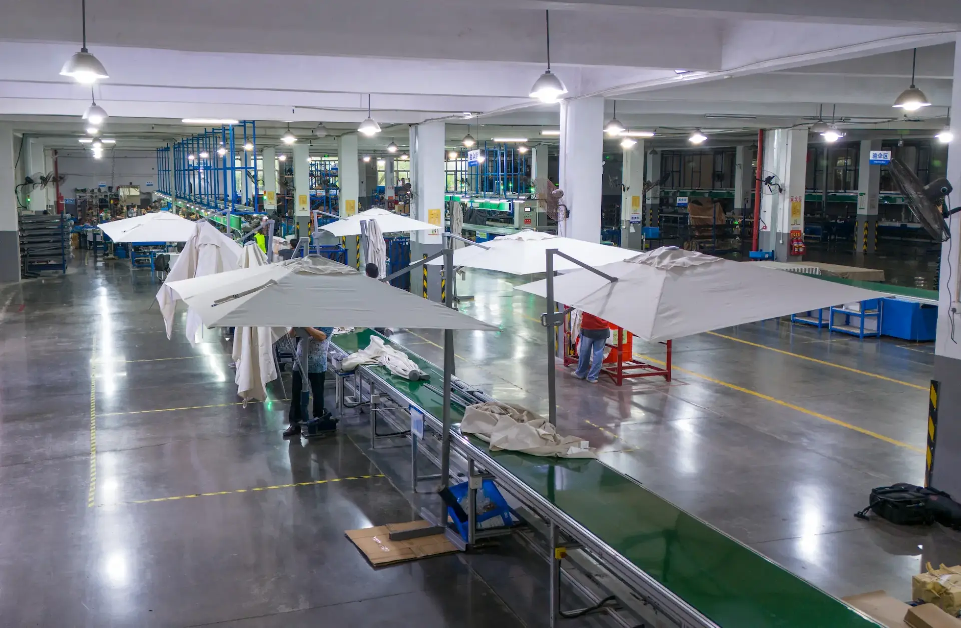 Inside the Tempo Manufacturing workshop showing the final assembly line for cantilever umbrellas, with technicians carefully fitting canopies to frames.