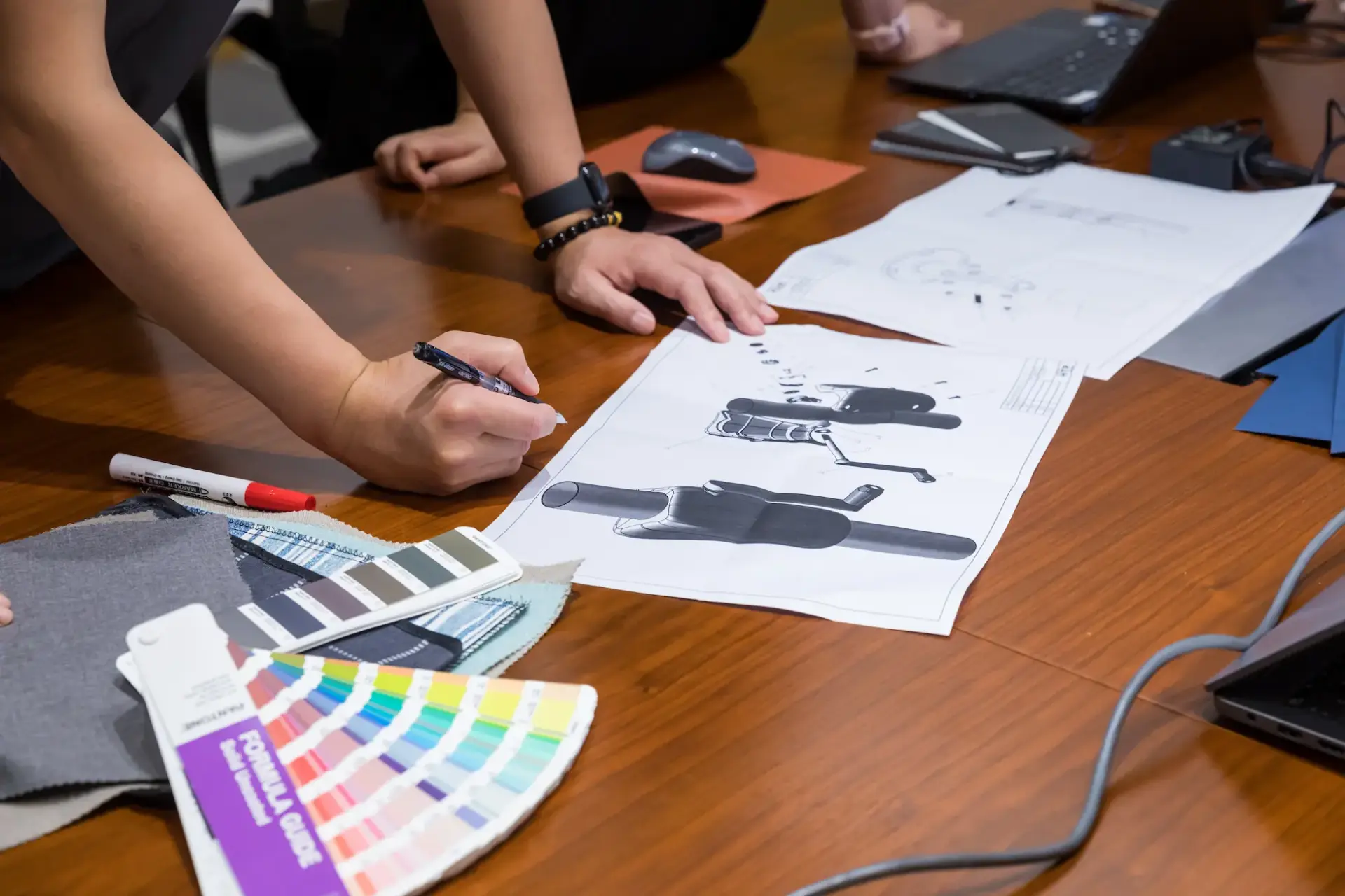 A close-up of the product design team collaborating, meticulously reviewing technical drawings and selecting materials from color and fabric swatches for a new umbrella design.