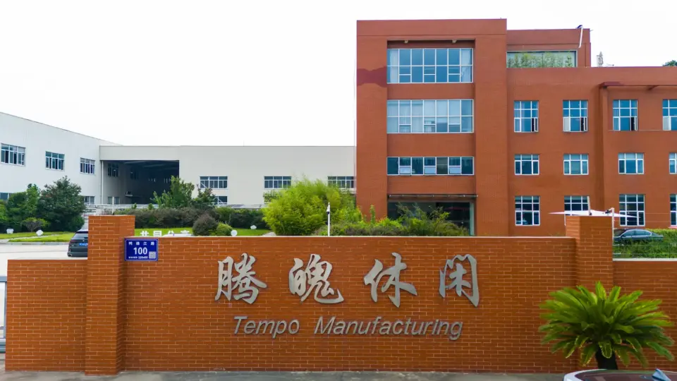 The entrance to the Tempo Manufacturing factory, featuring a brick sign with the company logo and modern production facilities in the background.