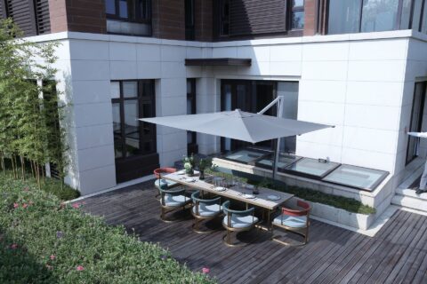 Tempo Aman umbrella in an outdoor dining setting, providing shade over a table.