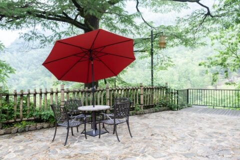 Tempo California umbrella in an outdoor setting with table and chairs.